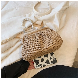 Detail of straw handbag with marble bead handle and dense weaving for beach vacation