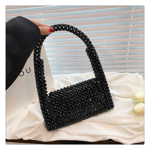 Detail of handmade black beaded handbag with glossy woven texture and retro evening style