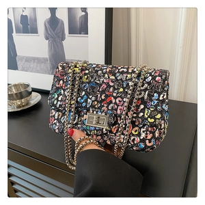 Detail of colorful graffiti crossbody bag featuring silver turn-lock and chain strap