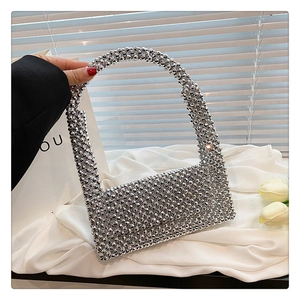 Close-up of a silver beaded luxury handbag with metallic finish on white silk