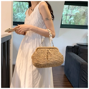 Close-up of handmade straw bag with elegant white irregular bead handle and metal hook