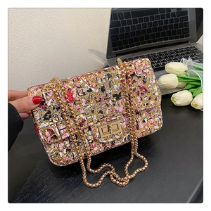 Detail of vintage graffiti pattern and gold twist lock on sequined chain crossbody bag