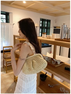 Detail of beige straw shell bag with large white bead strap and woven texture finish