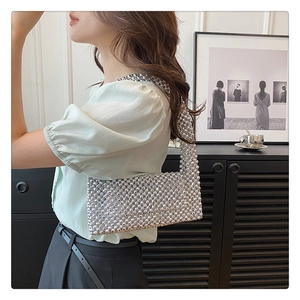 Detail of silver beaded handbag with metallic reflection and modern hobo structure