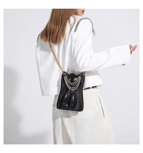 Gros plan du sac bandoulière créatif en cuir noir avec des chaînes dorées et argentées