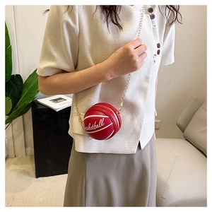 Close-up of a red basketball-shaped mini chain bag with gold hardware worn by a model
