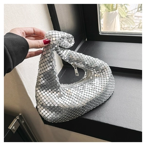 Détail d'un sac sous le bras à paillettes argentées avec poignée nouée et zip en métal