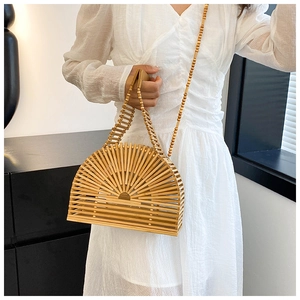 Détail d'un sac à main demi-lune en bambou avec bandoulière perlée sur robe blanche