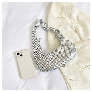 Détail du sac hobo à paillettes argentées avec téléphone et arrière-plan blazer