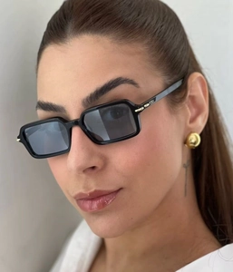 Close-up of rectangular black sunglasses with gold metal hinges and brand lettering