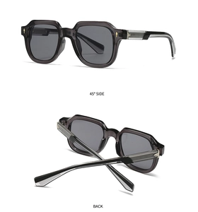 Detail view of black polygon sunglasses with gray lenses and gold hinge accents