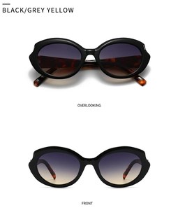 Detail view of futuristic wrap sunglasses with wavy black frames and gradient lenses