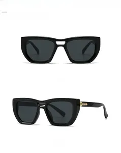 Detail of square black frame sunglasses featuring decorative golden metal hinges