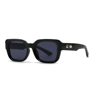 Close-up of black square sunglasses with metallic arrow detail and polished finish