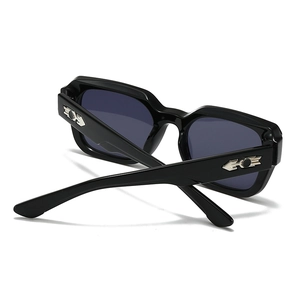Detail of square black sunglasses with blue lenses and silver arrow metal accents