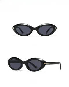 Close-up of black oval sunglasses featuring a golden T-shaped hinge detail and dark lenses