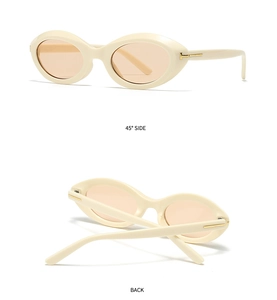Detail of cream oval sunglasses featuring golden T-shaped hinges and orange lenses