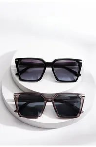Detail view of square wide-frame sunglasses in black and transparent grey colors