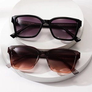 Square oversized sunglasses in black and translucent brown frames on a white platform