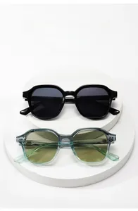 Gros plan de lunettes de soleil carrées avec montures noires et bleues sur un socle blanc
