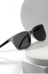 Macro view of square full-rim sunglasses with dark gray lenses on a white platform