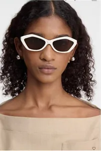 Close-up of white geometric cat-eye sunglasses with dark UV lenses on a fashion model