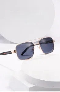 Détail de lunettes aviateur étroites avec monture en métal doré et verres polarisés gris