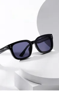 Detail view of black square frame sunglasses with silver diamond rivet accents on white pedestal