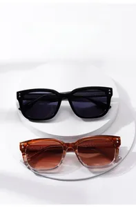 Detail view of square oversized sunglasses in black and gradient tea with metal rivet accents