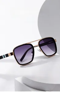 Detail of pilot sunglasses with gold metal frame, purple gradient lenses and striped temples