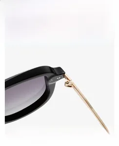 Detailed close-up of golden metal hinges and black frame on retro narrow sunglasses