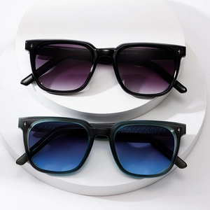 Modern square sunglasses in black and green frames with gradient lenses on white display