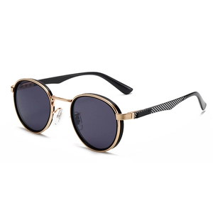 Modern retro round metal sunglasses with black lenses and gold frames in a flat lay view