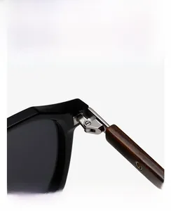 Close-up of durable silver metal hinge connecting black frame and wood grain temple arm