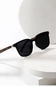 Detail of square black frame sunglasses with wood grain temples and metal rivets