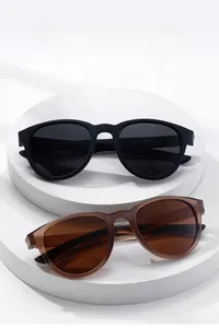 Top view of matte black and translucent brown round polarized sunglasses on white pedestals