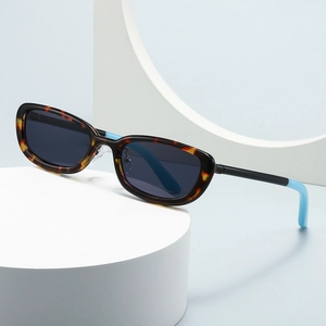 Retro oval sunglasses with tortoiseshell frame and blue accents on a white pedestal