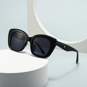 Modern oval sunglasses with thick black frames and white arrow rivets on white pedestal