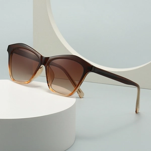 Retro cat-eye sunglasses with brown gradient lenses on a minimalist geometric pedestal