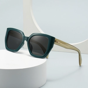 Modern oversized polygon sunglasses with dark green frames and tan temples displayed on white props