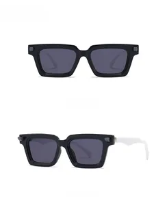 Close-up of black square sunglasses with silver metal rivets and grey UV lenses