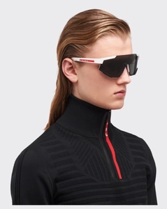 Detail view of oversized retro shield sunglasses and sporty black zip-up high neck top