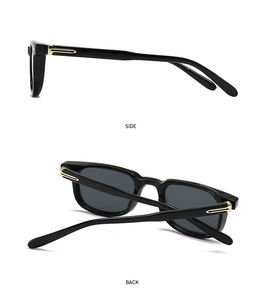 Close-up of black square sunglasses with decorative gold streamline metal on temples