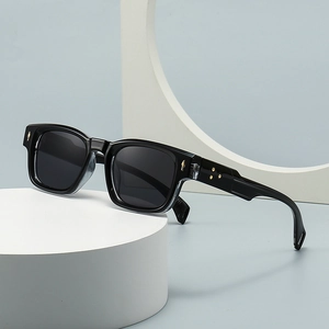 Retro black square sunglasses with gold star accents and grey lenses on white stand