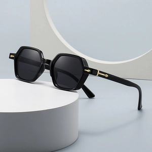 Modern black rectangle sunglasses with gold accents on a minimalist geometric display
