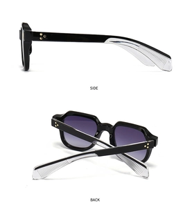 Détail de lunettes de soleil noires avec rivets fleurs dorés et verres dégradés violets