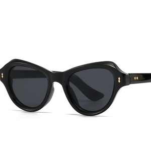 Schicke schwarze Schmetterlings-Cat-Eye-Sonnenbrille mit Goldnieten auf grauem Hintergrund