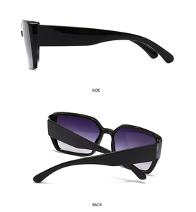 Detail view of square oversized sunglasses with black frames and purple gradient lenses