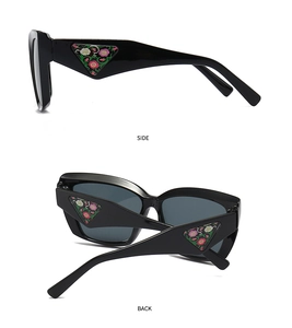 Detail of black sunglasses featuring a floral pattern inside a side triangle plaque