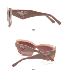 Detail view of pink cat-eye sunglasses with floral texture inside the triangular temple logo